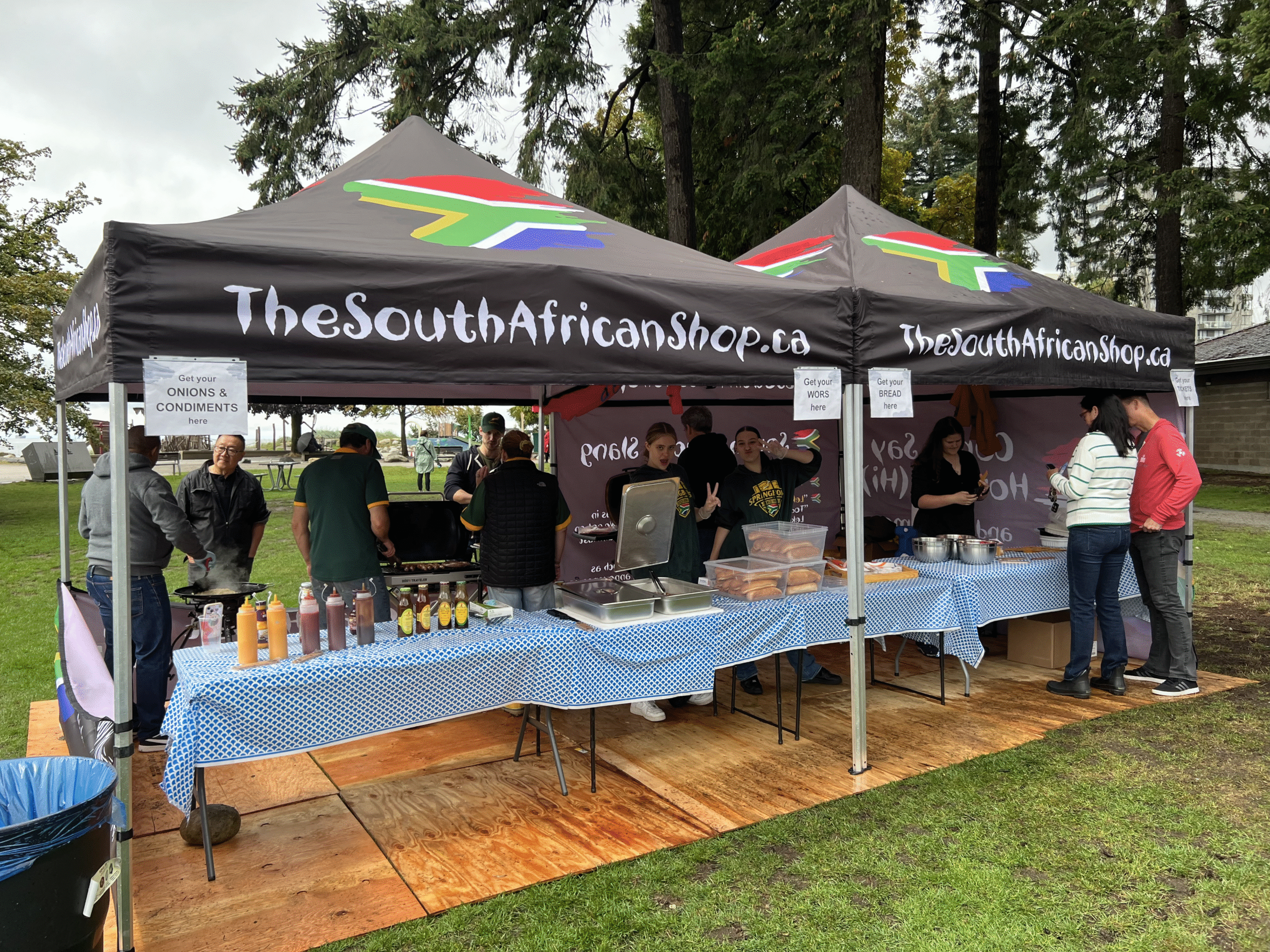 South African community members serving food under branded tents at Boerewors Roll Day in John Lawson Park, Vancouver